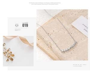 Detailed view of silver necklace with baguettes-cut zircons on marble stone display