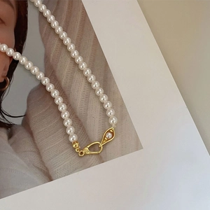 Macro detail of 925 sterling silver pearl necklace with unique gold clasp design