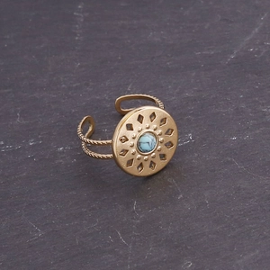 Detailed view of golden vintage ring featuring a round turquoise stone and hollow patterns