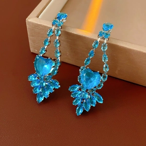 Detail of luxury heart earrings with bright blue crystals and zircons on jewelry box