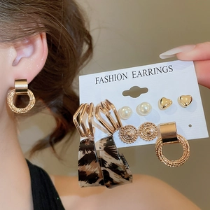 Detail shot of elegant earring set featuring pearls and gold hoops on display card