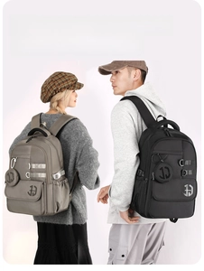 Detail of grey and black nylon backpacks with round pouch and cargo straps on models