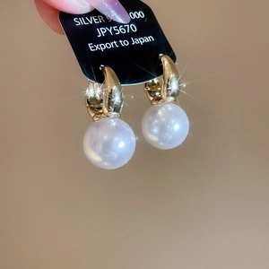 Macro shot of gold silver 925 earrings with large round white pearls and elegant hooks