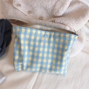 Close-up of blue and yellow checkered makeup bag with metal zipper on soft fabric background