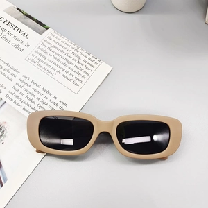 Detail of matte beige rectangular kids sunglasses with grey lenses on a grey background