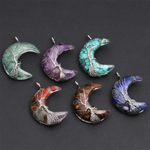 Handmade Tree of Life moon pendants with natural crystal stones on a textured black surface
