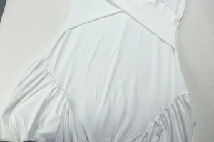 Detail of white pleated V-neck maxi dress with cross halter design and side ruching texture