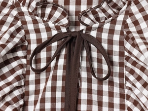 Détail du col d'une chemise à carreaux avec un nœud marron et texture du tissu