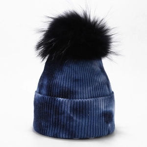 Detail of navy tie-dye knit beanie featuring a fluffy black pompom and ribbed texture