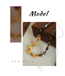 Détail du collier à maillons en or avec perles d'agate sur un présentoir en bois