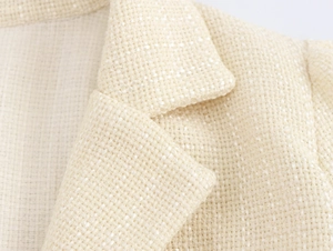 Vista macro dettagliata del colletto del blazer in tweed crema e della trama del tessuto