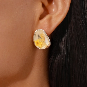 Minimalistische silberne Harz-Ohrstecker mit gelben Trockenblumen am Modell