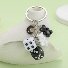 Detail of keychain featuring dice, bear charms, and moon pendant on white ceramic base