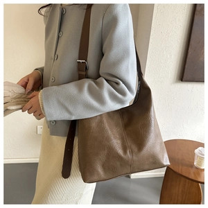 Detail of a brown PU leather tote bag with adjustable shoulder strap on female model