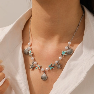 Close-up of necklace featuring silver chain, white pearls, and starfish charms on a model