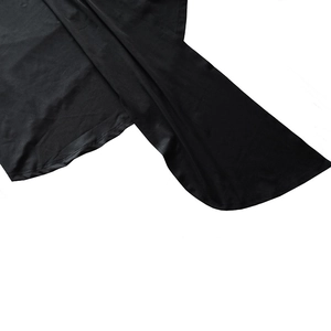 Detail view of the black dress hemline showing high-quality stitching and smooth fabric texture