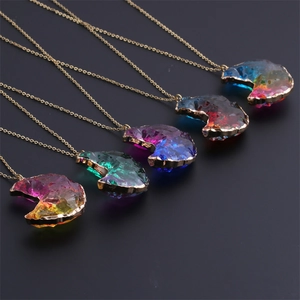 Détail de cinq colliers croissant de lune en cristal coloré avec bordures dorées sur fond noir