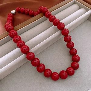 Close-up of red glass bead necklace with silver clasp on a grey jewelry display tray