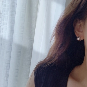 Minimalist silver spherical stud earrings worn by a model in soft natural lighting