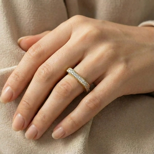 Gros plan de bagues en or serties de diamants sur une main contre un tissu en maille