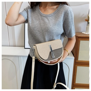 Close-up of beige and gray fabric handbag with metal lock and adjustable shoulder strap