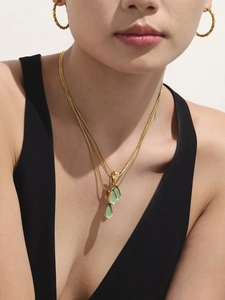 Détail d'un collier doré multi-rangs avec pendentif goutte verte et boucles d'oreilles