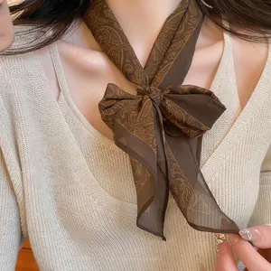 Brown paisley silk scarf necklace tied in a bow over a beige ribbed sweater for women
