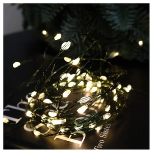Macro detail of warm white LED fairy lights on dark green wire with festive decor