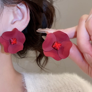 Detailed close-up of red flower earrings with matte petals and square center crystals