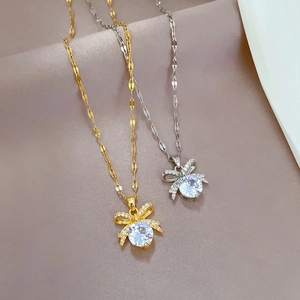 Elegant gold and silver bow pendant necklaces with zircon inlay on silk background