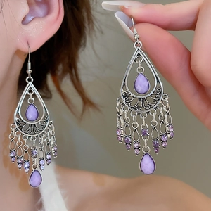 Detail of vintage bohemian silver earrings with purple teardrop stone and tassels