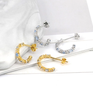 Close-up of gold and silver S925 C-shaped earrings inlaid with light blue cubic zirconia