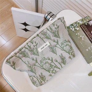 Detailed view of green floral fabric pouch with simple wish label on white surface