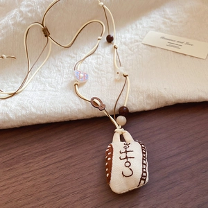 Close-up of canvas coffee cup pendant with embroidery on vintage fabric necklace