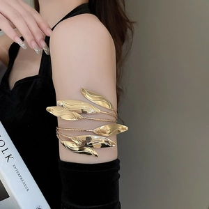 Detail of a golden multilayer leaf arm cuff featuring a polished wrap-around design