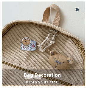 Detalle de mochila de pana con broche de oso de peluche y accesorios de oso espacial