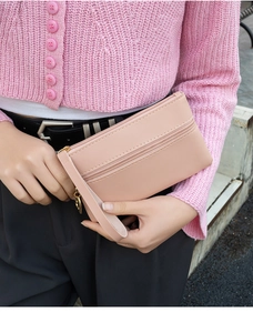 Close-up of pink faux leather clutch with zipper pocket and wrist strap detail