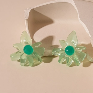 Detailed close-up of translucent green floral resin earrings on a textured stone prop