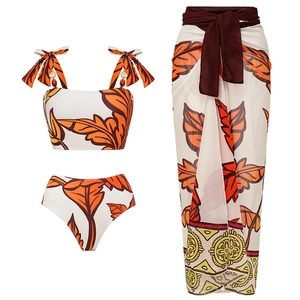 Three-piece one-shoulder swimsuit set with orange leaf print and matching beach sarong