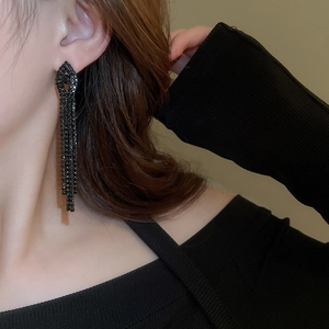 Close-up of black tassel drop earrings with sparkling rhinestones on model side profile