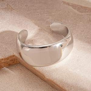 Macro shot of silver wide open bangle with high-polished mirror finish on a stone surface