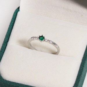 Macro view of adjustable silver ring featuring a green zircon center stone in a gift box
