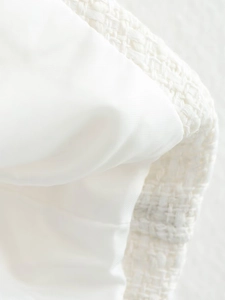 Macro shot of white tweed fabric texture and smooth satin lining of the cape jacket