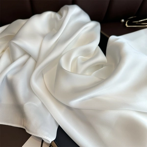 Macro view of white satin fabric texture with elegant silky folds and glossy finish