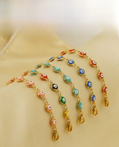 Detail of four colorful 18K gold plated evil eye bracelets on satin background