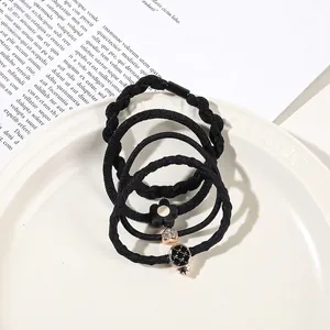 Close-up of black elastic hair ties set with heart and flower charms in a white dish
