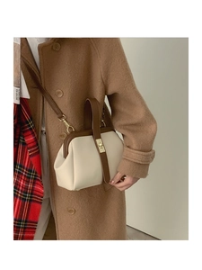 Detail view of retro crossbody bag in beige and dark brown leather on autumn coat