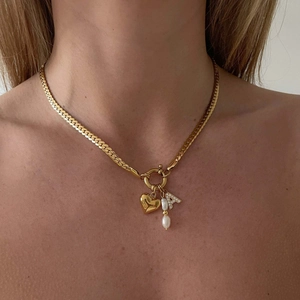 Detail of 18k gold paperclip chain necklace with heart pendant, pearl and letter A charm