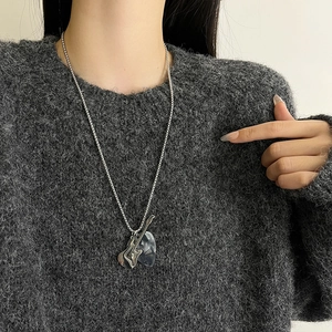 Detail of silver chain necklace with dual layered irregular pendants worn by a model