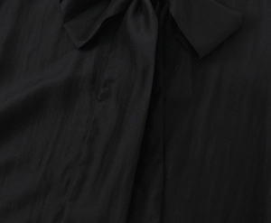 Detailed macro view of the black bow-tie neckline and vertical ribbed fabric texture